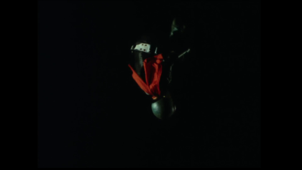 アニメ『仮面ライダー』第4話。真っ暗な背景の中、赤いマフラーをなびかせて空中を舞う仮面ライダー1号のスタントシーン。